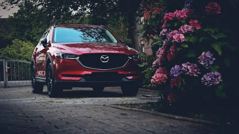 Picture of Sleek Red Mazda CX-5 in the park with flower in front of it 